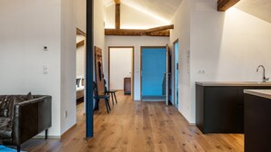 Un interior moderno con piso de madera, un sofá, una mesa de comedor y una zona de cocina.
