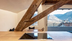Una cocina con una viga de madera, una estufa moderna y vistas a montañas.