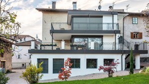 Ein modernes, zweistöckiges Haus mit Balkon, Garage und gepflegtem Rasen.
