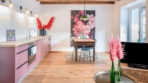 Eine moderne Küche mit Holzbalken, einem Essbereich mit Tisch und Stühlen sowie einem großen Blumenbild an der Wand.