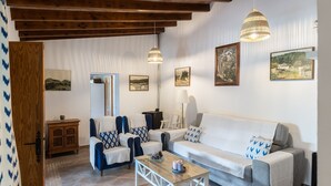 A living room with a sofa, chairs, a coffee table, and artwork on the walls. - Villa Can Tomas with Mountain View, Garden, Pool & Wi-Fi (Pollença)