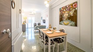 A dining area with a wooden table, floral chairs, and a large floral painting on the wall. - Luxury Penthouse in prime central Athens Thissio (Athina)