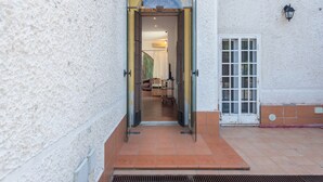 Un umbral abierto que da a una habitación con una cama y una silla, un suelo de baldosas y un aplique de pared.