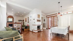 Amplia sala de estar con chimenea, comedor con mesa y cocina con televisor y asientos.
