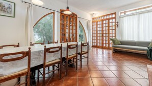 Un comedor con una mesa larga, sillas y un sofá.