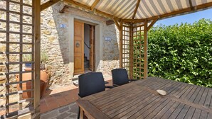 A wooden table with two chairs, a stone wall, and a wooden door. - 'La Ripa - Apartment I Ghiri' with Shared Pool & Wi-Fi (San Gimignano)