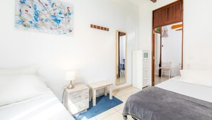 Een hotelkamer met twee bedden, een klein nachtkastje met een lamp, een blauw vloerkleed, een spiegel en een kaart aan de muur.