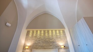 A room with a stone wall, a white ceiling, and a wooden wardrobe.