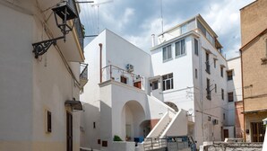 A narrow street with white buildings, a visible staircase, and a truck parked on the street.