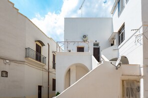 Una calle estrecha con edificios blancos, balcones y cielo despejado.