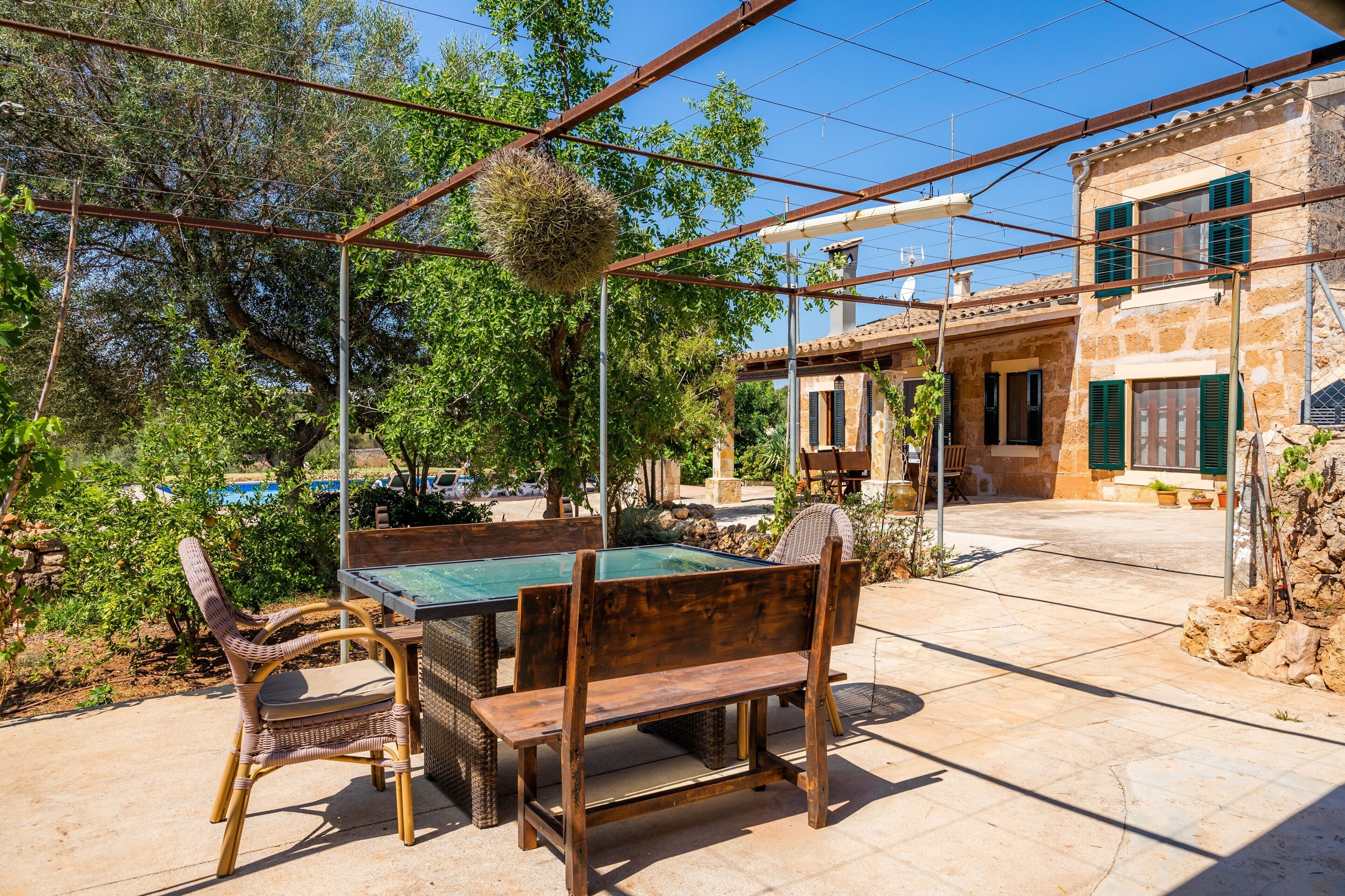 A patio with a pool table, wicker chairs, and a wooden bench.