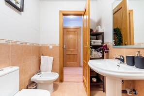 Une salle de bain équipée de toilettes, d’un bidet, d’un lavabo et d’un miroir.