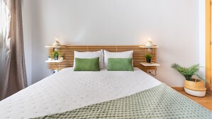 Ein ordentlich eingerichtetes Schlafzimmer mit einem Bett, Nachttischen und einer Topfpflanze.