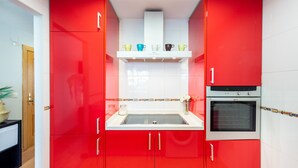Eine Küche mit roten Schränken, einer weißen Arbeitsplatte und einem eingebauten Backofen.