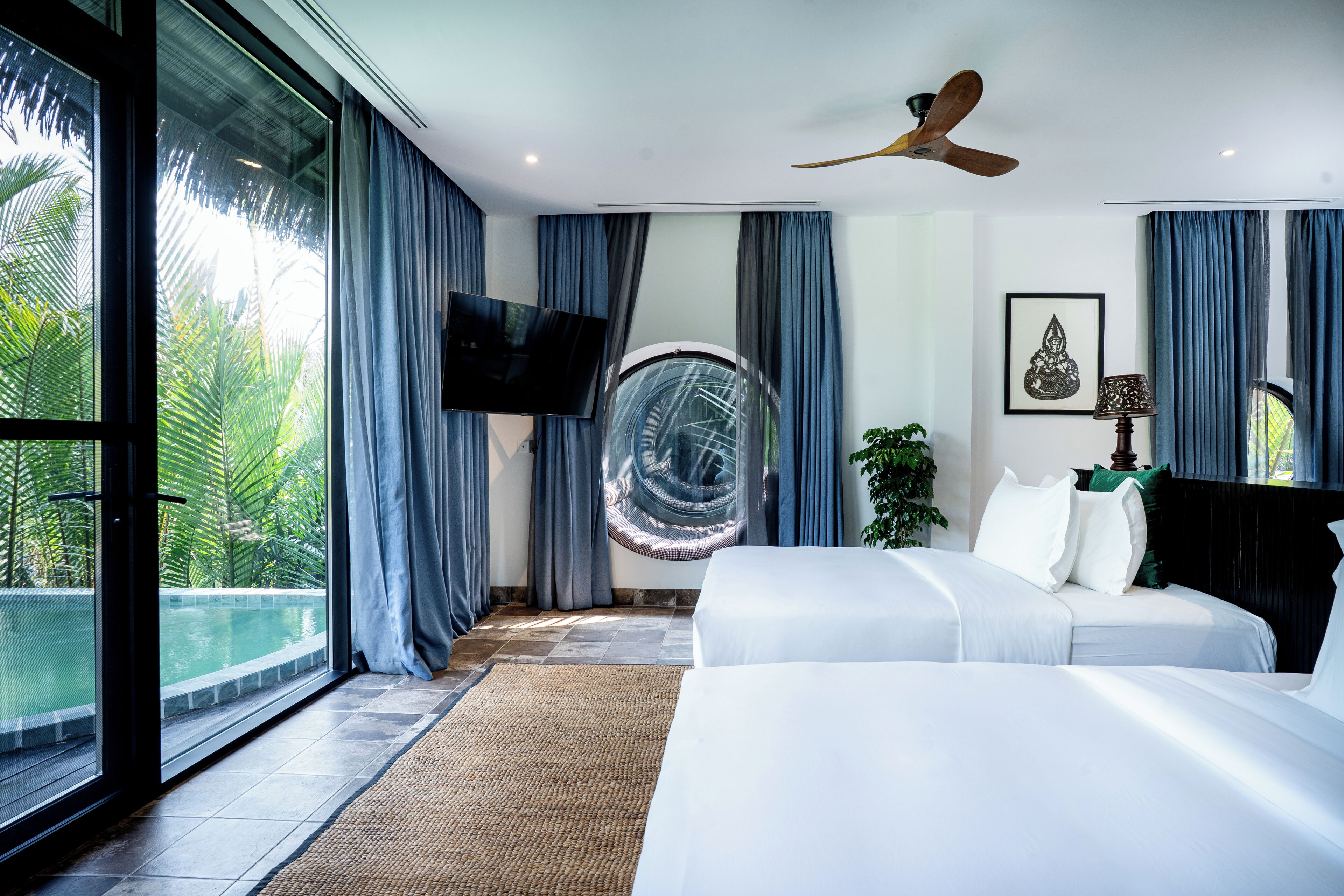 A modern hotel room with a large bed, a ceiling fan, a TV, and a view of a swimming pool.