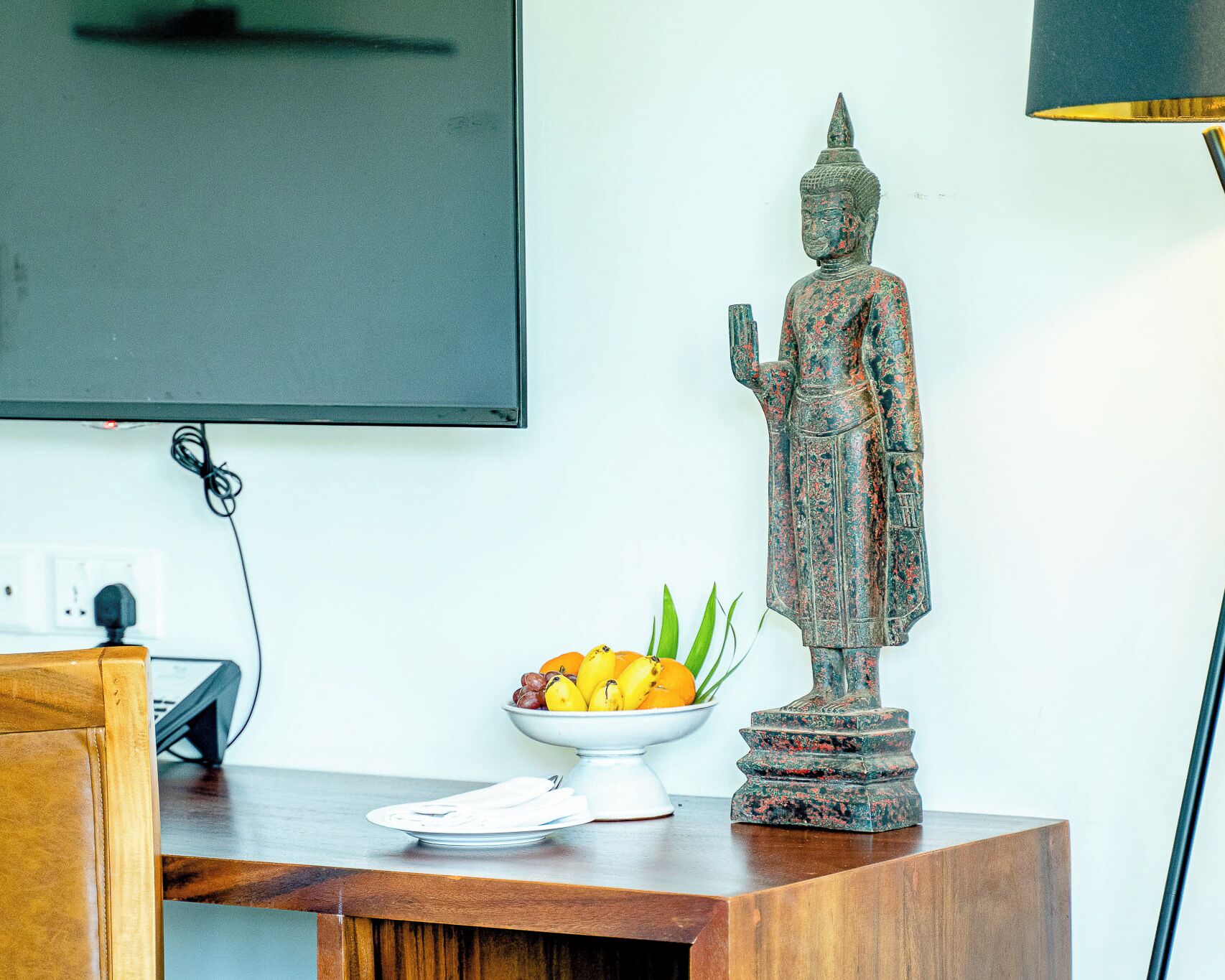 Una estatua sobre una mesa de madera, con un frutero a su lado.
