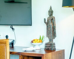 Una estatua sobre una mesa de madera, con un frutero a su lado.