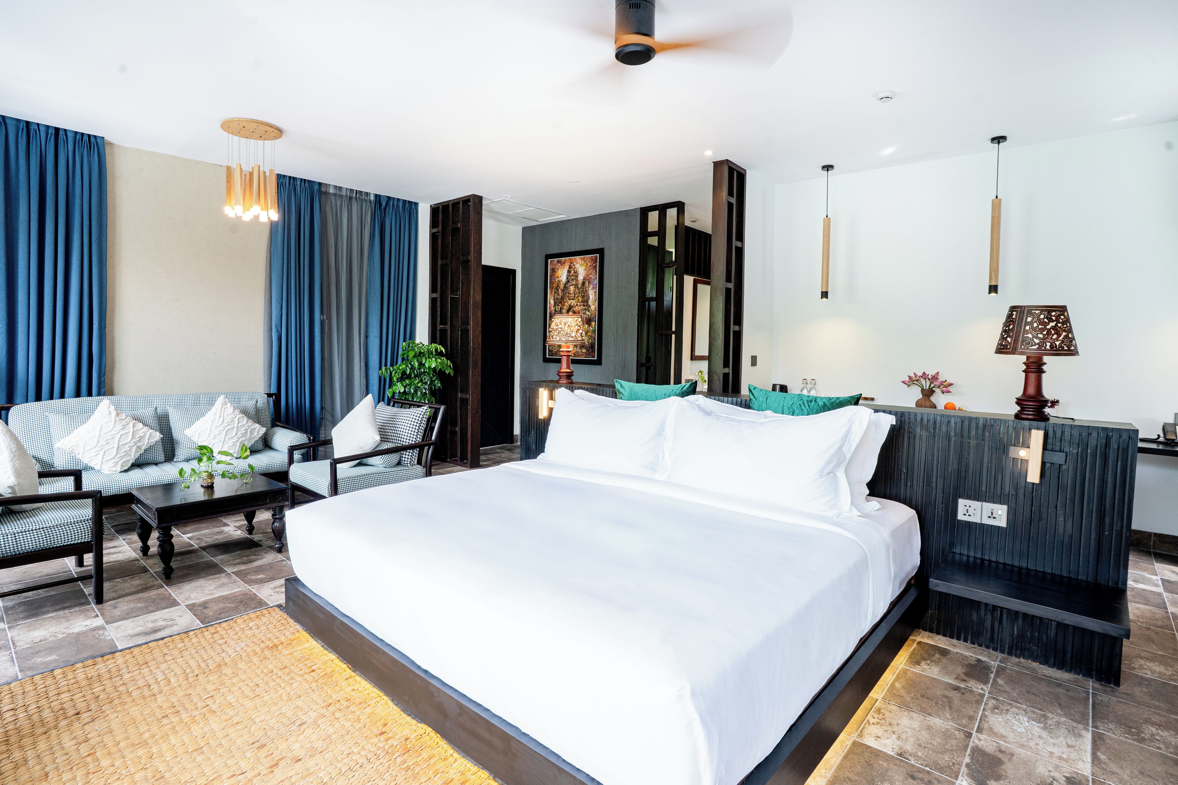 A modern hotel room with a large bed, a sofa, a coffee table, and a desk.
