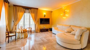 Un salon avec un canapé, un téléviseur, une petite table et une chaise.