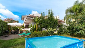 Un jardin avec une piscine, du mobilier d’extérieur et une maison.