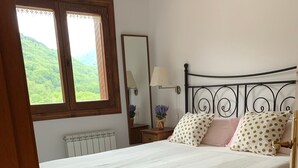 Een slaapkamer met een bed, een raam, een radiator en een nachtkastje met een lamp.