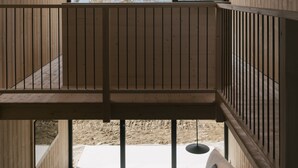 Ein modernes Interieur mit Holzboden, einer Couch, einem kleinen Tisch und Bergblick durch große Fenster.