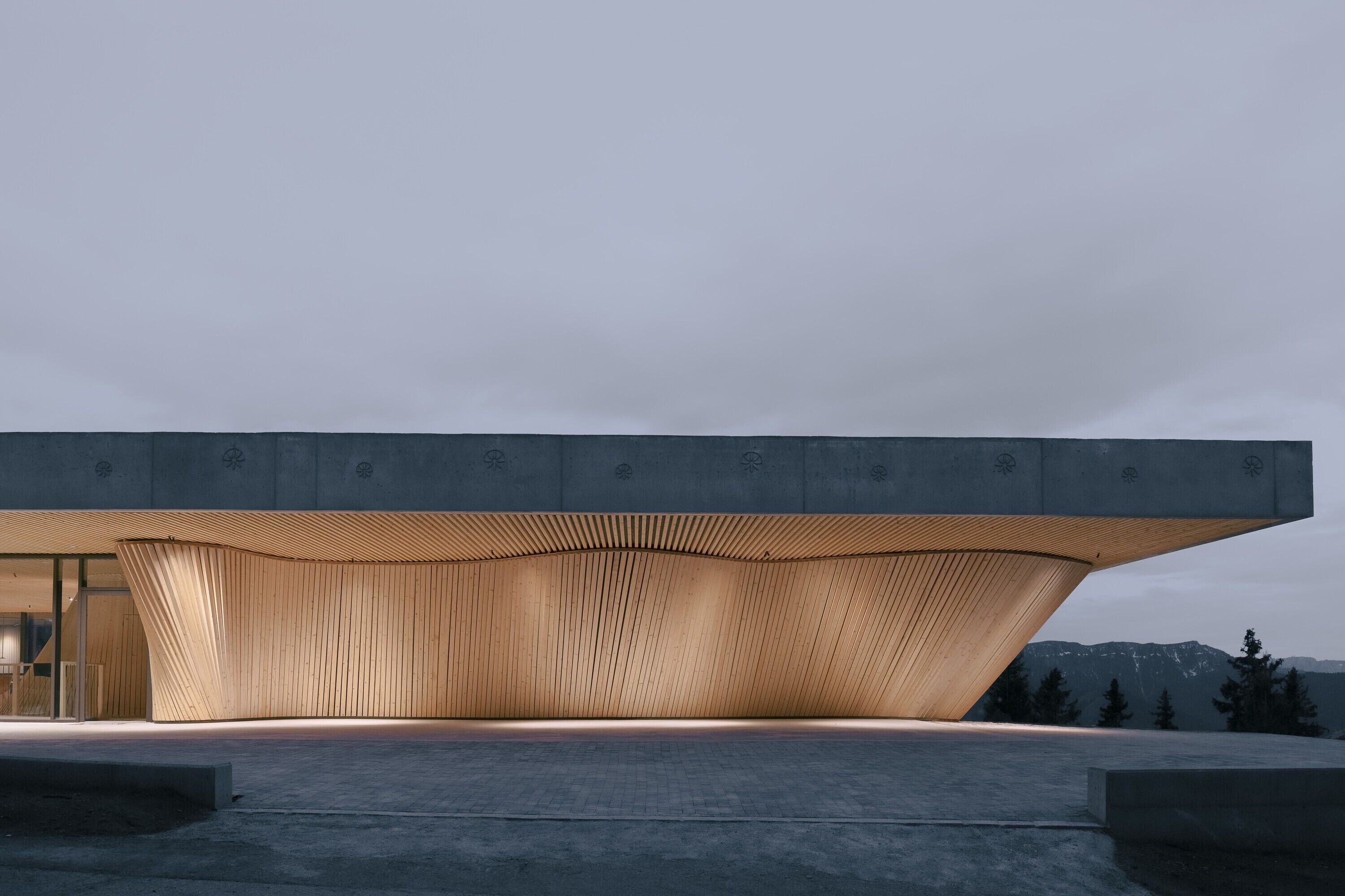 Un edificio moderno con una struttura a tettoia dalla forma particolare e una facciata piana.