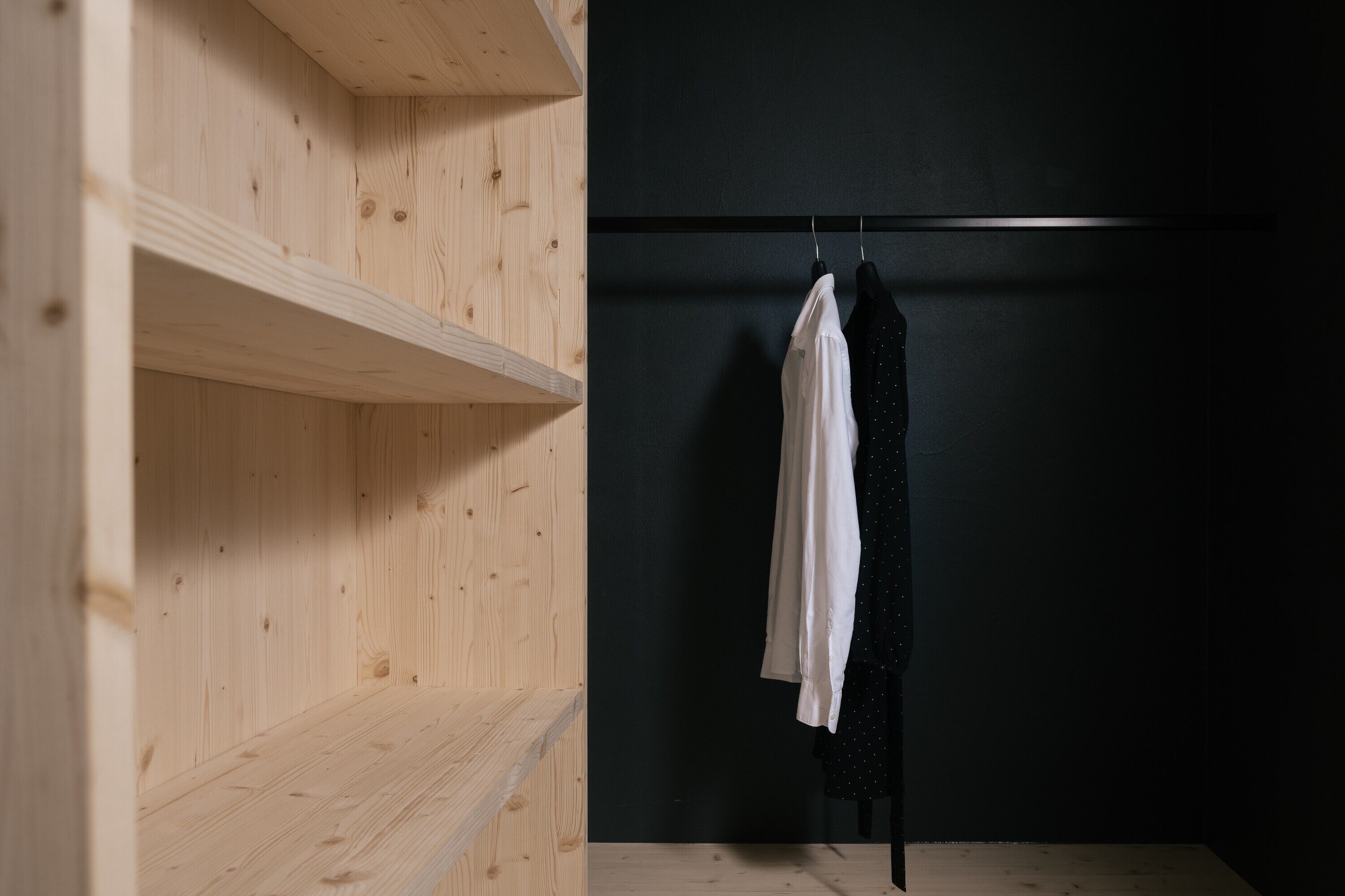 A room with wooden shelving and a black wall.