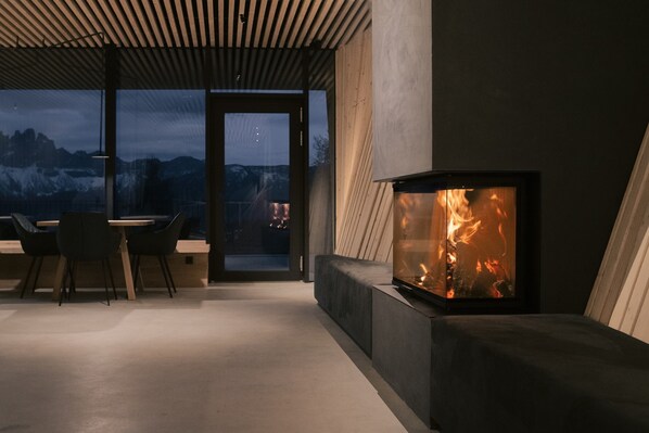 A modern interior with a fireplace, a dining area, and a view of mountains.