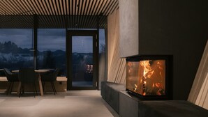 A modern interior with a fireplace, a dining area, and a view of mountains.