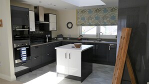 A modern kitchen with a central island, dark cabinetry, and a skylight.