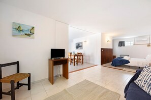 A modern room with a bed, a desk with a TV, a dining area, and a painting on the wall. - Apartment "A Cerca - E" with Shared Pool, Garden & Wi-Fi (Lagos)