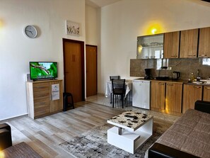 Een moderne keuken met houten kastjes, een inbouwvaatwasser en een eethoek met een tafel en stoelen.