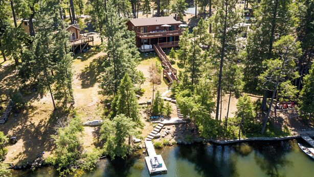 An aerial view of a lodge with a dock, surrounded by dense forest. - The Big Easy - Lakefront Only 1 mile to Popular Marina Beach! by Yosemite Region Resorts (Groveland)