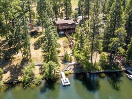 An aerial view of a lodge with a dock, surrounded by dense forest.