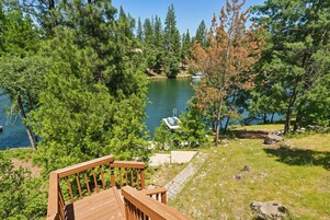 A wooden deck overlooking a lake with boats, surrounded by dense trees.
