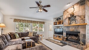 A living room with a sofa, TV, fireplace, and ceiling fan. - Star of the Mountain - The Star of Your Vacation by Yosemite Region Resorts (Groveland)