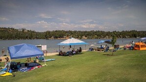 A lakeside camping area with tents, a covered seating area, and a grassy field. - The Hideout - Pet Friendly - The Perfect Spot for a Relaxing Yosemite Vacation by Yosemite Region Resorts (Groveland)