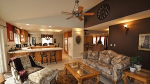 A spacious living room with a sofa, armchair, and coffee table. A kitchen area with a bar and chairs is visible in the background. - Yosemite Villa - Only 0.3 Miles from Lake Lodge Beach and Playground by Yosemite Region Resorts (Groveland)