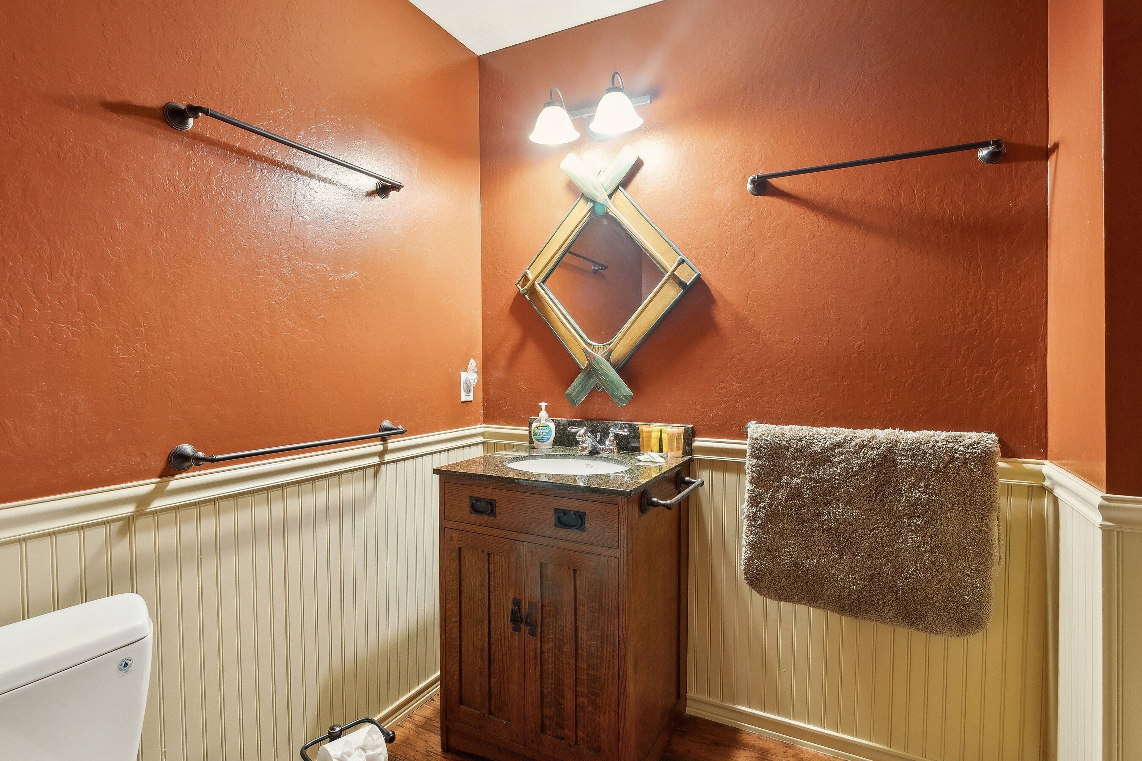 A bathroom with a wooden vanity, a mirror, and two wall-mounted light fixtures.