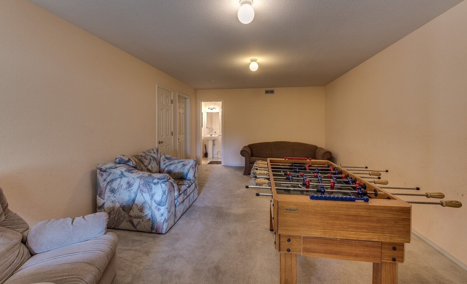Een gezellige woonkamer met een tafelvoetbalspel, een bank en een divan.