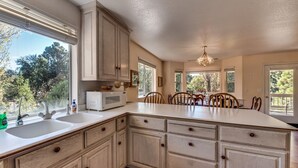 A kitchen with a large island, white cabinets, and a view of the outdoors. - Casa Del Lago - Only 200 Yards from the Beach by Yosemite Region Resorts (Groveland)