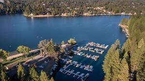 An aerial view of a marina with boats docked, surrounded by dense forest and a calm lake. - Casa Del Lago - Only 200 Yards from the Beach by Yosemite Region Resorts (Groveland)