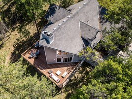 An aerial view of a modern house with a large deck, a chimney, and a garage.
