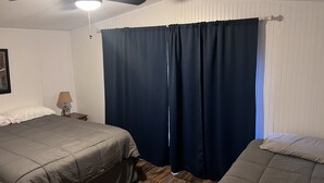 Ett sovrum med två sängar, en takfläkt och ett nattduksbord med en lampa.