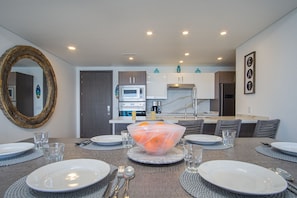 Enjoy meals in this stylish dining area with a large mirror, dining table, and modern kitchen.
