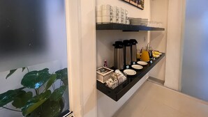 A breakfast bar with coffee mugs, plates, and a juice pitcher. - Pousada Mar de Luna (Penha)