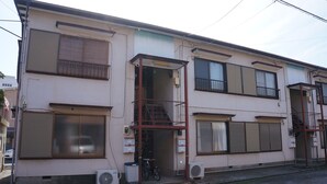 A two-story building with a balcony, a bicycle parked outside, and two air conditioning units on the ground floor. - Oyado Ichigo Nisho 27 IG1 (Ito)