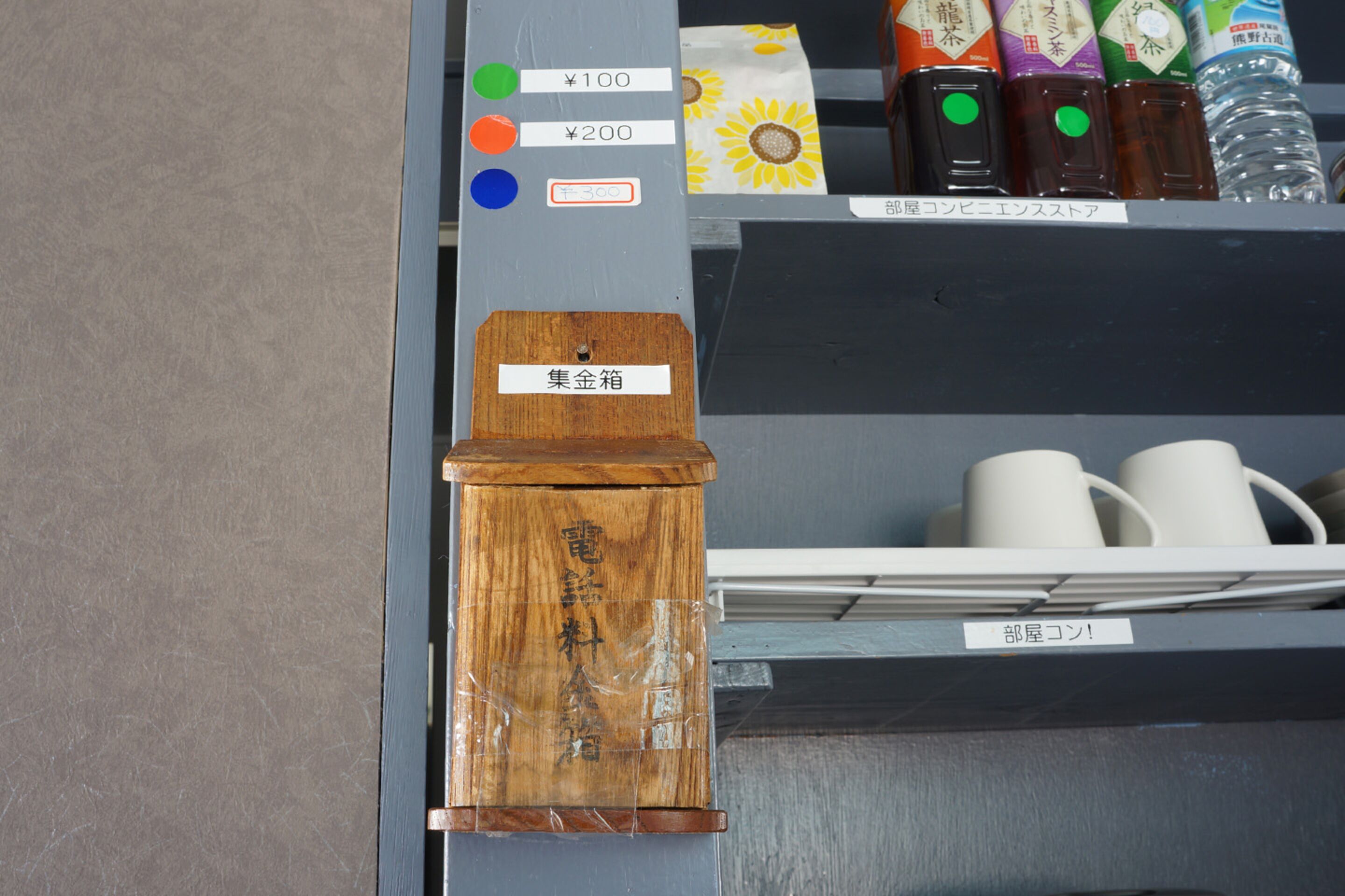 Un meuble en bois avec une étiquette indiquant « 集金箱 » (boîte à pièces).