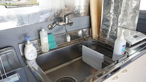 A modern kitchen with a stainless steel sink, a dish rack, and various toiletries. - Oyado Ichigo Nisho 27 IG1 (Ito)